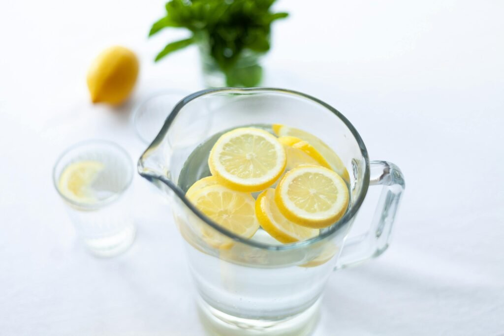 Top-down view of lemon slices in a glass pitcher filled with water, offering a refreshing drink option.